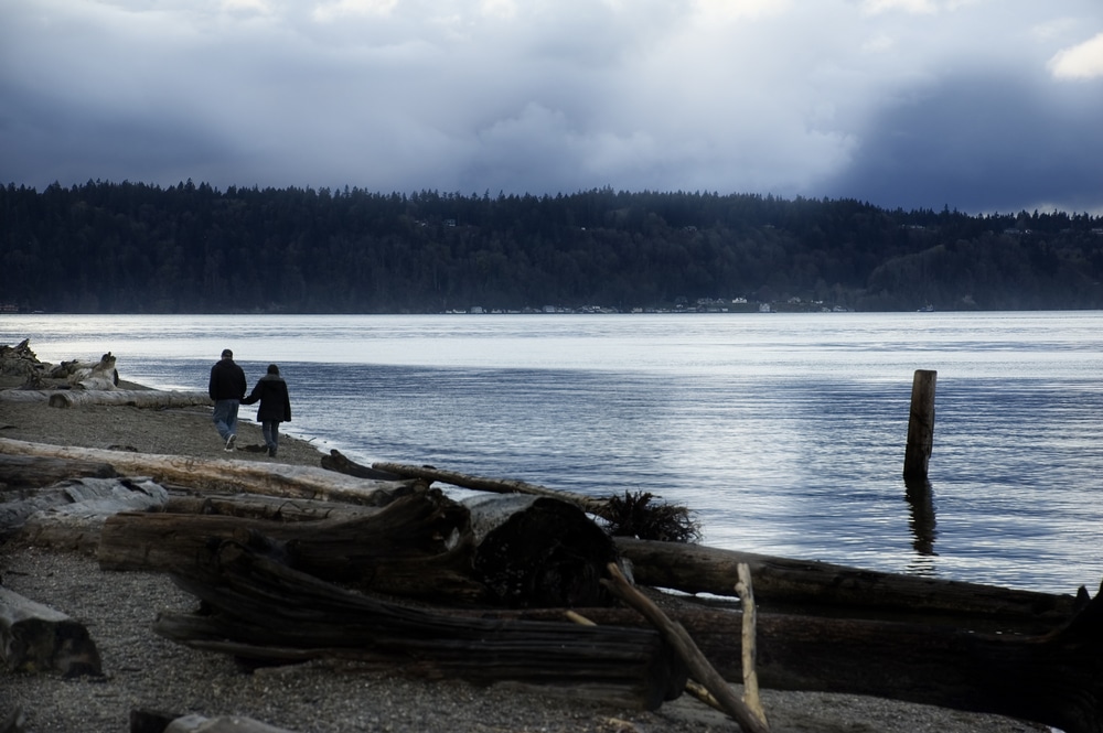 Couple walking on a Washington Beach - one of the most romantic things to do in Sequim, WA while staying at our Sequim Lodging